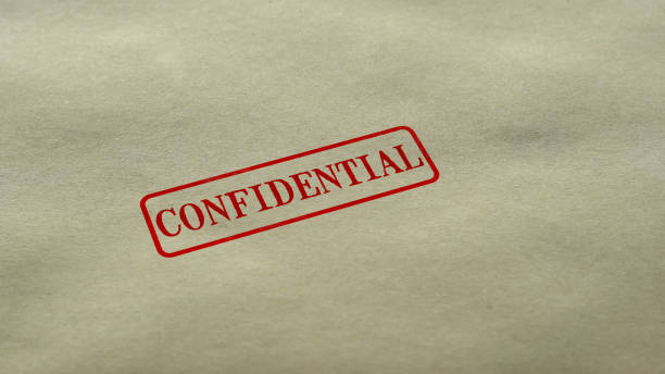 A manilla folder with the word CONFIDENTIAL stamped on it in red ink, with the rubber stamp that stamped it, above.