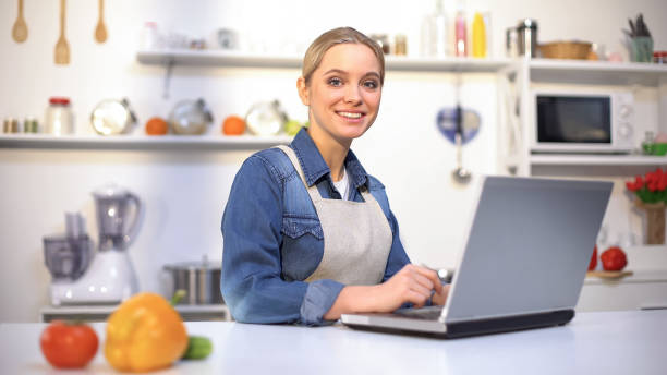 istock Happy pretty woman searching cooking recipe in internet, using laptop, kitchen 1159017882