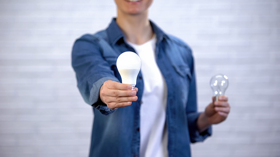 Chica elige la bombilla led de ahorro de energía en lugar de la lámpara incandescente, la eficiencia photo