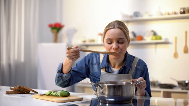 istock Beautiful lady tasting soup while cooking, preparing food for dinner, dieting 1159018022