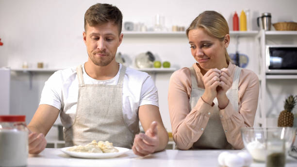 couples drôles regardant la pâte crue, les mauvaises cuisinières, les cours de cuisine pour des amateurs - cooking fail photos et images de collection