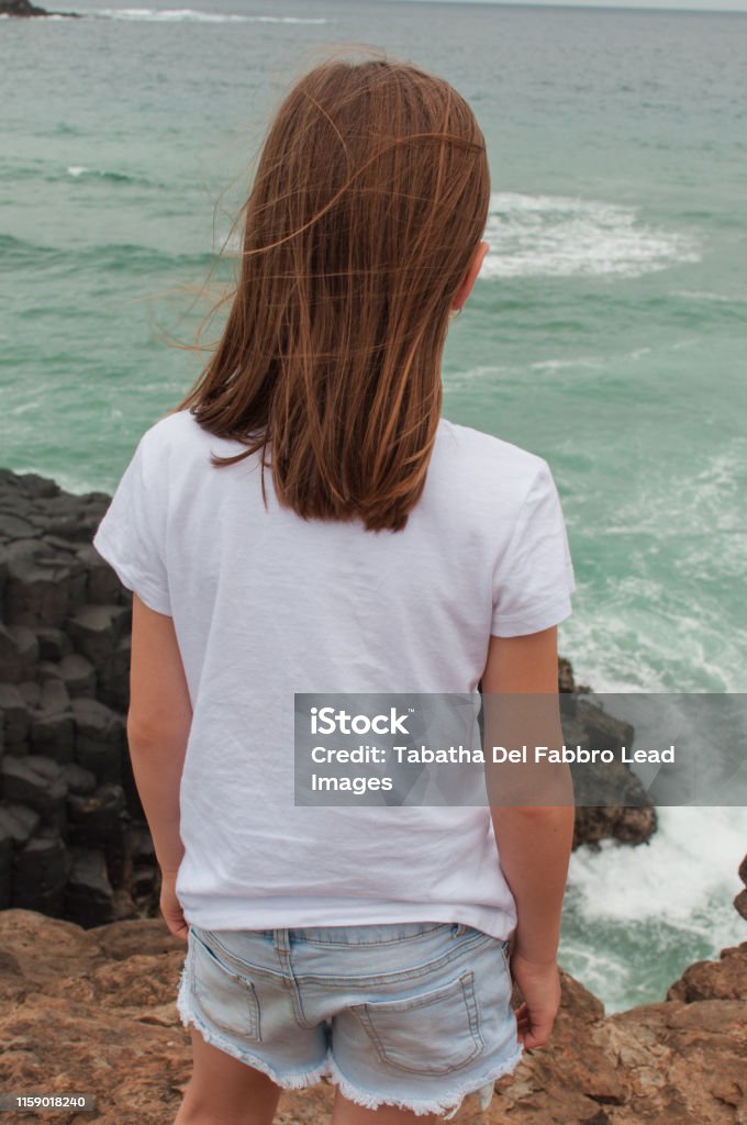 Girl overlooking cliff to the ocean alone. Girl overlooking cliff to the ocean alone, Australia. Active Lifestyle Stock Photo