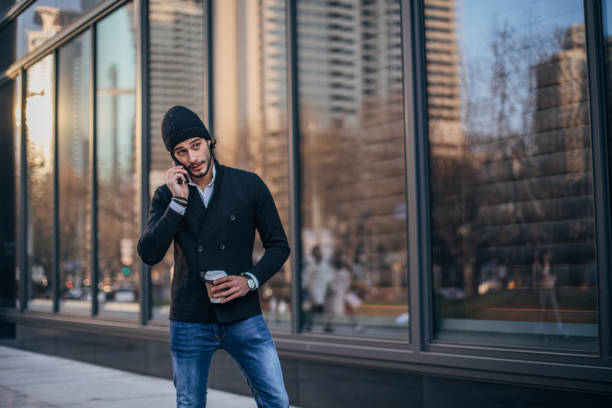 istock Handsome man holding coffee and talking on phone 1159018893