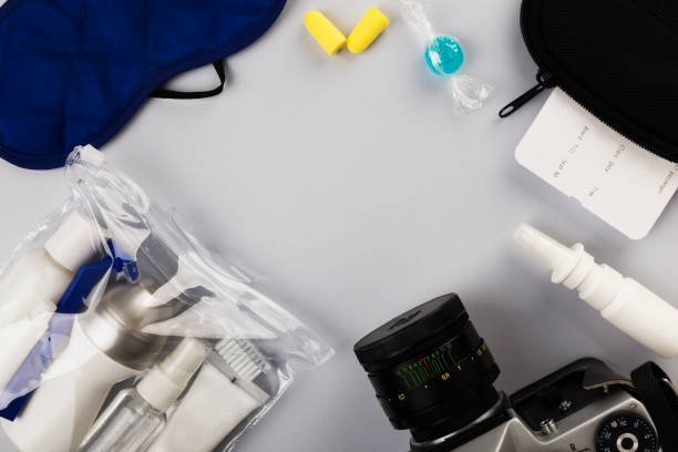 istock Set for flight small bottles with cosmetics, sleep mask, camera, earplugs, nasal spray, air ticket and documents on gray background. Top view, copy space 1159019203