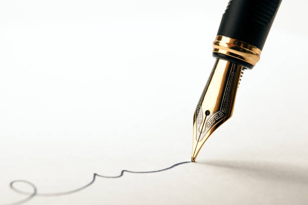 金色の万年筆が白い紙のクローズアップに署名を残す - fountain pen ストックフォトと画像