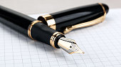 golden fountain pen on the notepad on a table closeup
