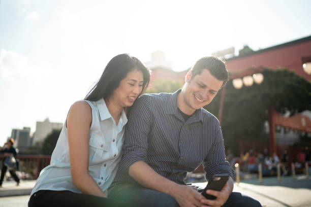 istock Happy couple using phone in the city 1159023313