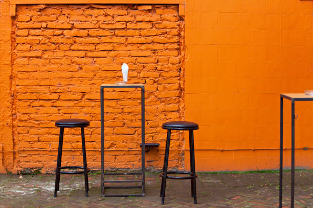 Black bar chairs and orange brick floor laid in fishbone style, covered with moss. Hipster retro style minimalism.