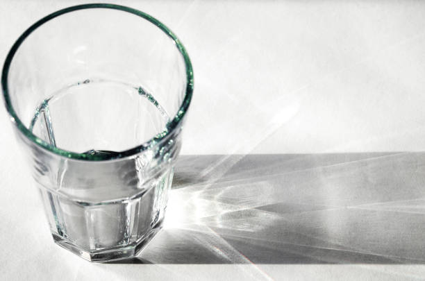 istock Water glass with strong shadows on white background 1159023717