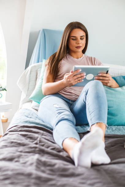 istock Young woman relaxing on the bed and using digital tablet 1159026658