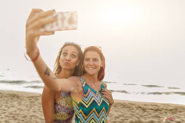 istock Girl friends at sea: selfie on the beach at sunset 1159026798