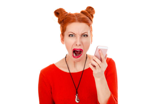 istock woman screaming looking at camera holding mobile phone 1159028241