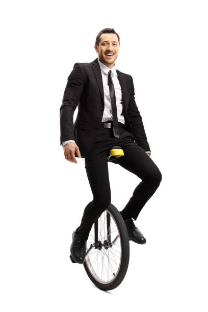 istock Businessman riding a unicycle and smiling at the camera 1159029212