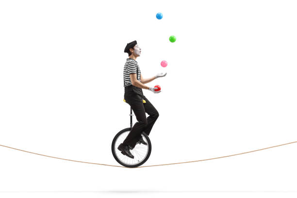 Mime riding a unicycle on a rope and juggling with balls Full length profile shot of a mime riding a unicycle on a rope and juggling with balls isolated on white background juggling stock pictures, royalty-free photos & images