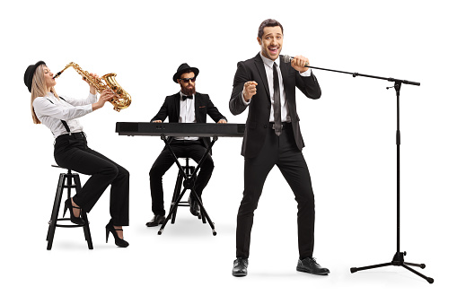 Full length shot of a woman playing sax, man playing a keyboard and a male singer singing on a microphone isolated on white background