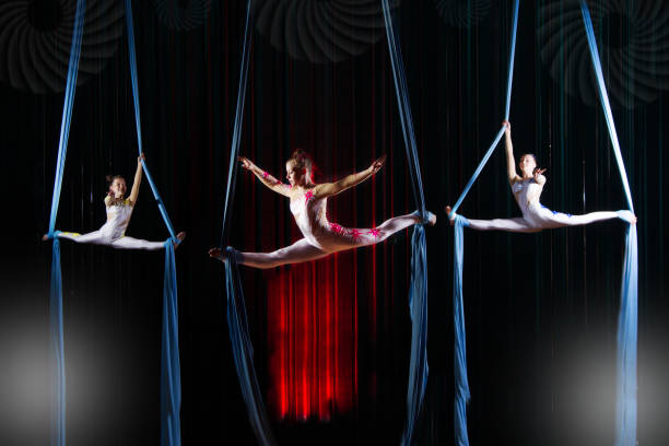 Circus actress acrobats performance on canvases. Team girls perform acrobatic elements in the air.