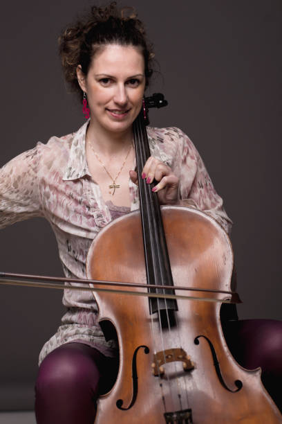 istock Beautiful dark haired female cellist with her instrument 1159032407