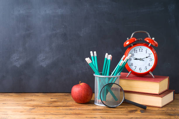 istock Back to school background with pencils, apple, books and alarm clock over chalkboard 1159034095
