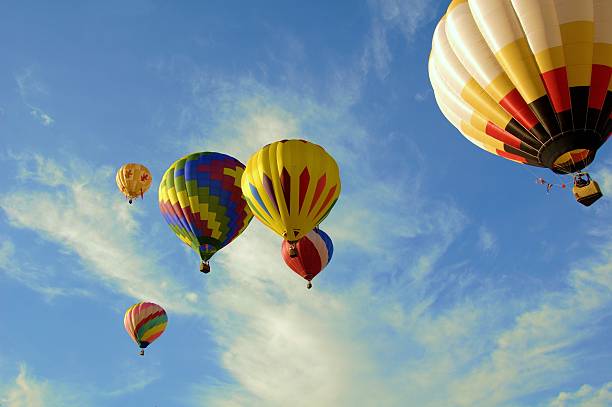 A group of 6 bright colorful balloons soar in the air.