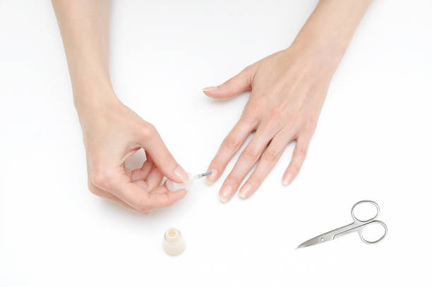 istock The girl makes a manicure beige lacquer. White background. 1159039301