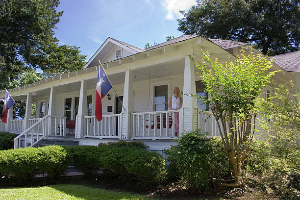 Old historical home in southern USA. Front porch. Woman. Texas. Historical home that was relocated and turned into a museum.  Museum depicts county history.  Texas flags adorn the posts.MORE LIKE THIS... in lightbox below. cropped pants photos stock pictures, royalty-free photos & images