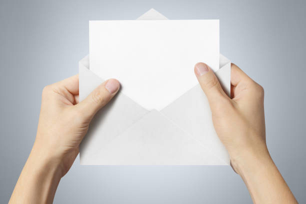 istock Hand holding an open white envelope with a blank paper inside 1159045416