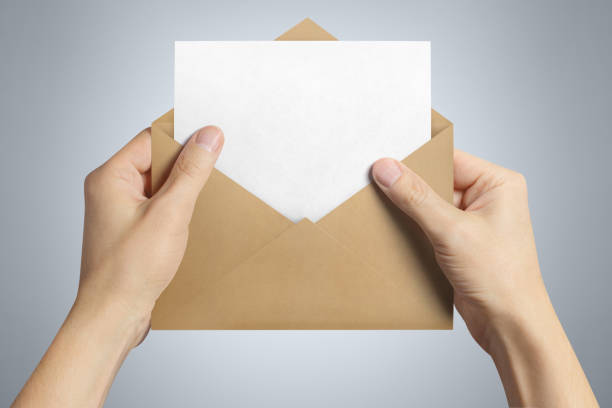 istock Hand holding an open brown envelope with a blank paper inside 1159045419
