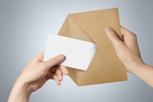 istock Hands pulling a blank sheet of paper (letter, ticket, flyer, invitation, coupon, banknote, etc.) out a brown envelope 1159045423