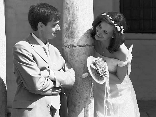 Happy couple standing together after the wedding ceremony. There is a wall of castle on background.