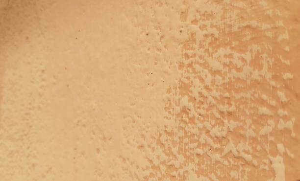 istock Abstract background of two-colored painted layers on old rough wall surface. Grunge textures closeup. Orange and beige colored backdrop. 1159046353