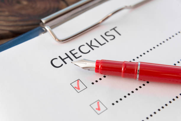istock checklist, red pen on a wooden background close-up. 1159049175