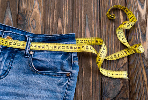 istock jeans, centimeter on a wooden background. diet. waist 1159049940