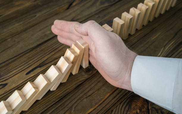istock a male hand stopping the domino effect. 1159049999