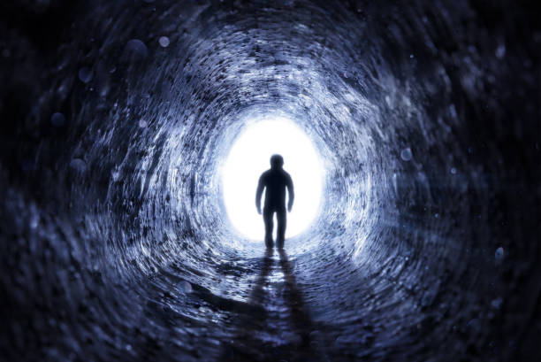 homme aîné marchant à la lumière au bout du tunnel - espoir après la vie - spirituality light tunnel light at the end of the tunnel photos et images de collection
