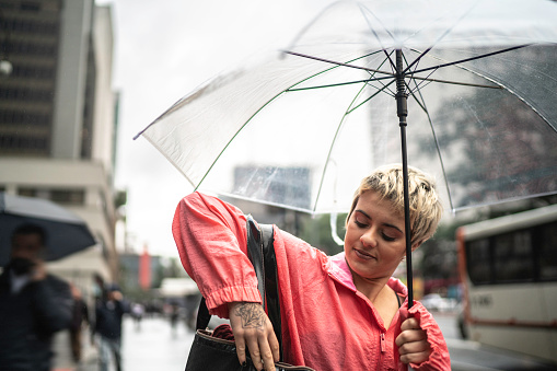 Chilean young woman walking in the street in a rainy day