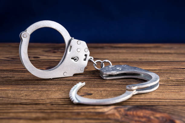 istock handcuffs on wooden background 1159051247
