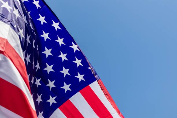 istock American Flag close up against blue sky 1159053237