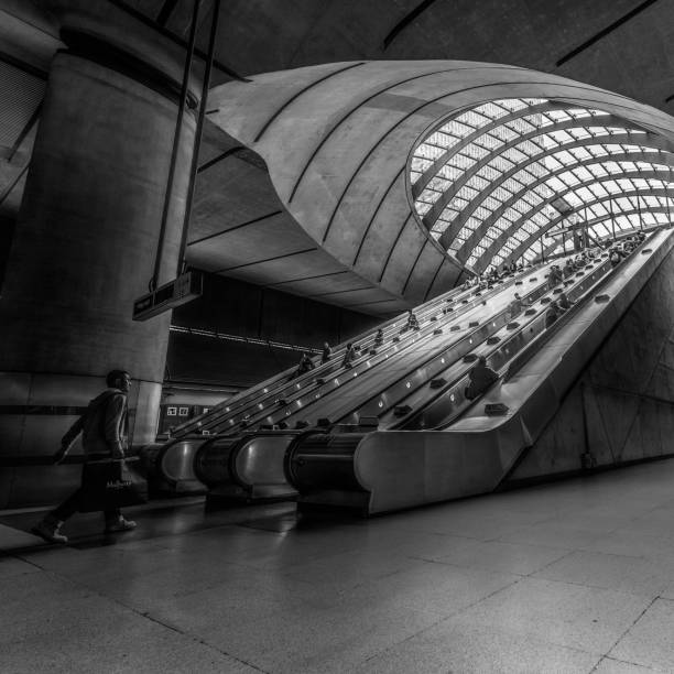 canary wharf underground station in london's docklands business and finance district with people walking up and down the escalators - docklands light railway imagens e fotografias de stock