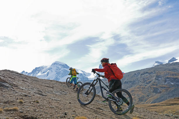 istock Mountain bikers push their bikes up an alpine slope below the Matterhorn mountain 1159059625