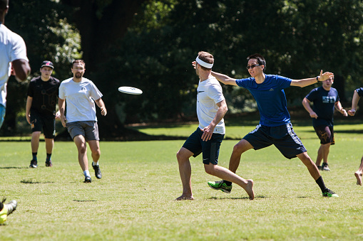 Atlanta, GA, USA - July 28, 2018:  A man tosses a frisbee to a teammate in an ultimate frisbee game in Piedmont Park on July 28, 2018 in Atlanta, GA.