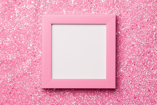 Pink frame for a photo or inscription with white sticker inside  on a shiny glitter background.