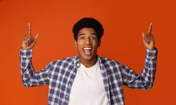 istock Cheerful Teen Guy Pointing Upwards and Looking at Camera 1159063503