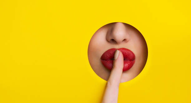 shh! red lips look through hole in yellow paper shh! red lips look through hole in yellow paper shh! red lips look through hole in yellow paper sh - whispering finger on lips secrecy silence photos et images de collection