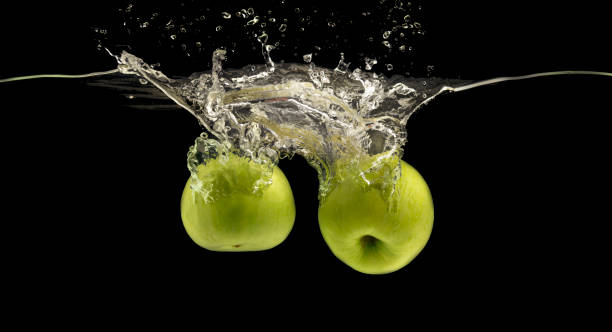 istock Two green apples sinking into water with air bubbles 1159063778
