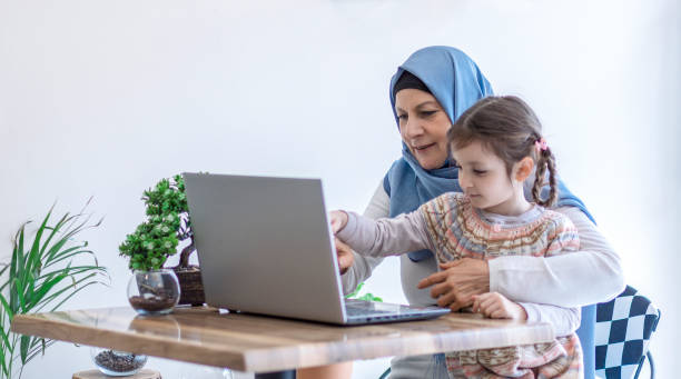 istock Muslim mom watching laptop with her daughter sitting on lap 1159064568