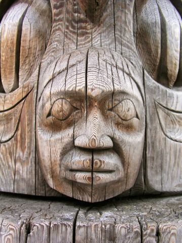 Close-up view of a totem pole carving. Shallow depth of field, focus on face.