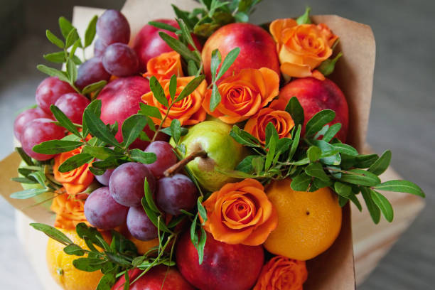 bouquet of fruits and flowers. green pear, nectarine, red grapes, orange rose, pistachio, orange. gray wooden background. - gift orange green package imagens e fotografias de stock
