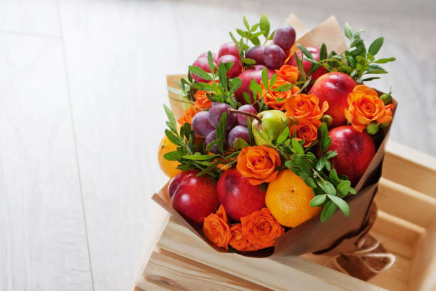 bouquet of fruits and flowers. green pear, nectarine, red grapes, orange rose, pistachio, orange. gray wooden background. - gift orange green package imagens e fotografias de stock