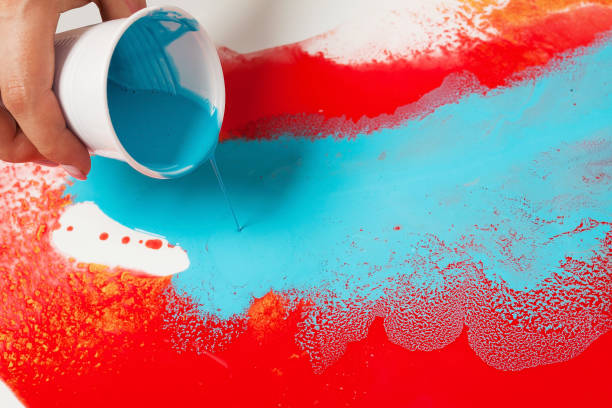 How to make acrylic painting. Work in progress. Female hand holding a plastic cup with blue paint.