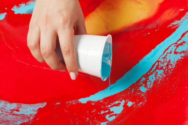 istock How to make acrylic painting. Work in progress. Female hand holding a plastic cup with blue paint. 1159075636